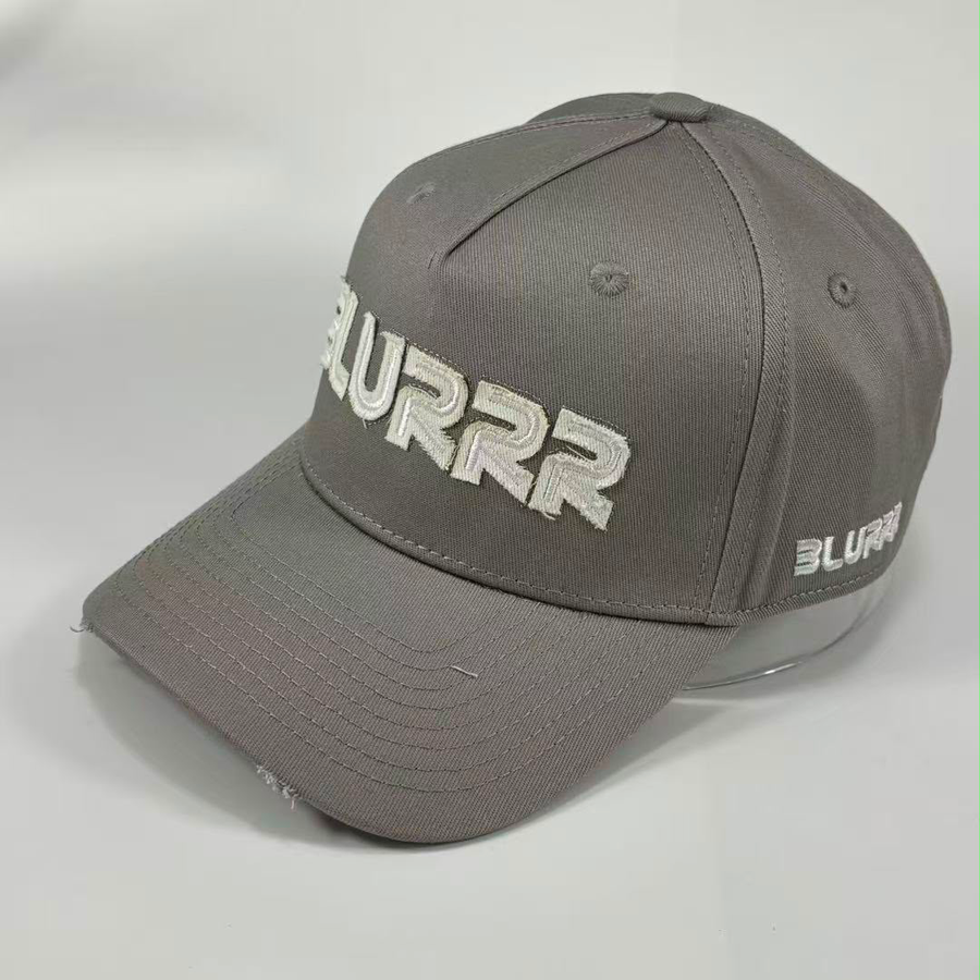 A grey baseball cap with 'BLURRR' embroidered in white on the front and side, displayed on a clear stand against a light gray background.