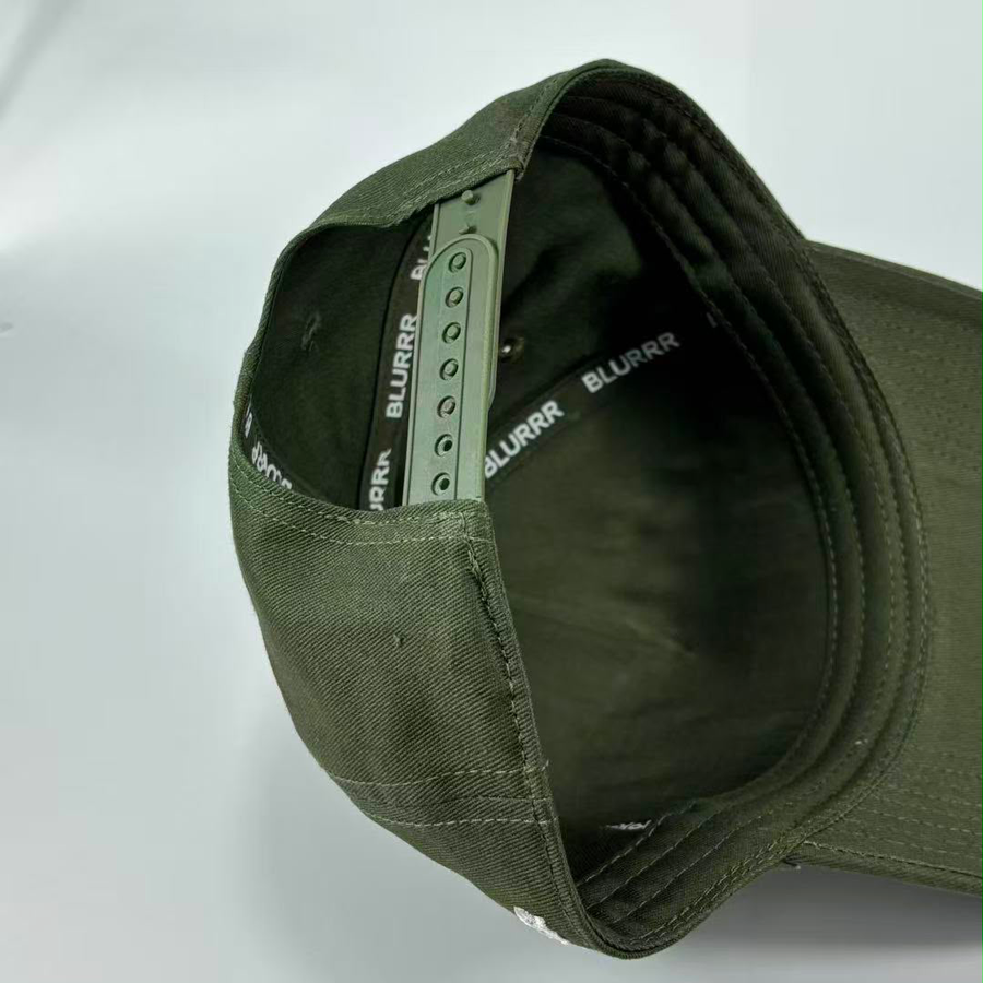 Close-up of the interior of an olive green cap, showing the adjustable inner band with printed BLURRR branding and ventilation eyelets.