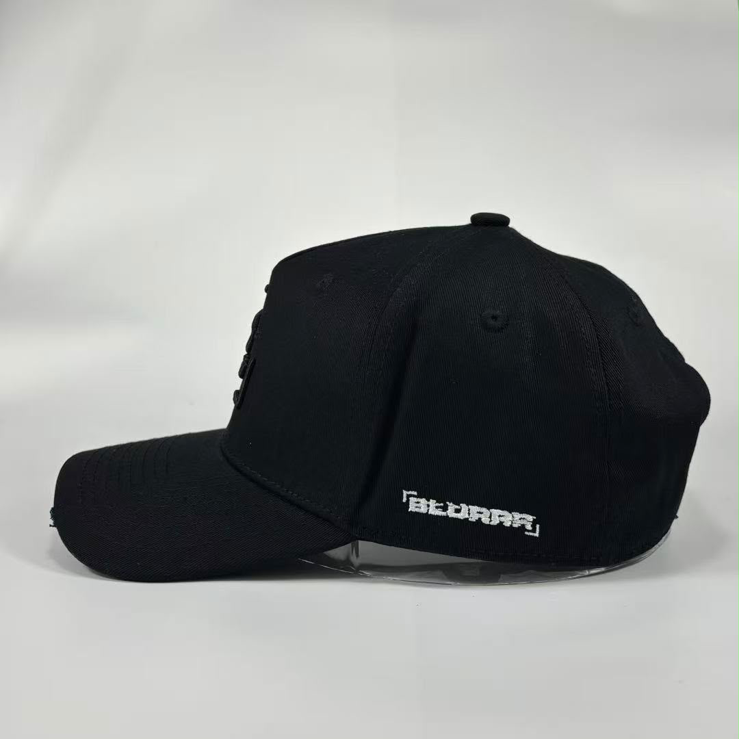 A black baseball cap with a curved brim, featuring a white stylised 'BLURRR' logo on the side, displayed on a clear stand against a light grey background.