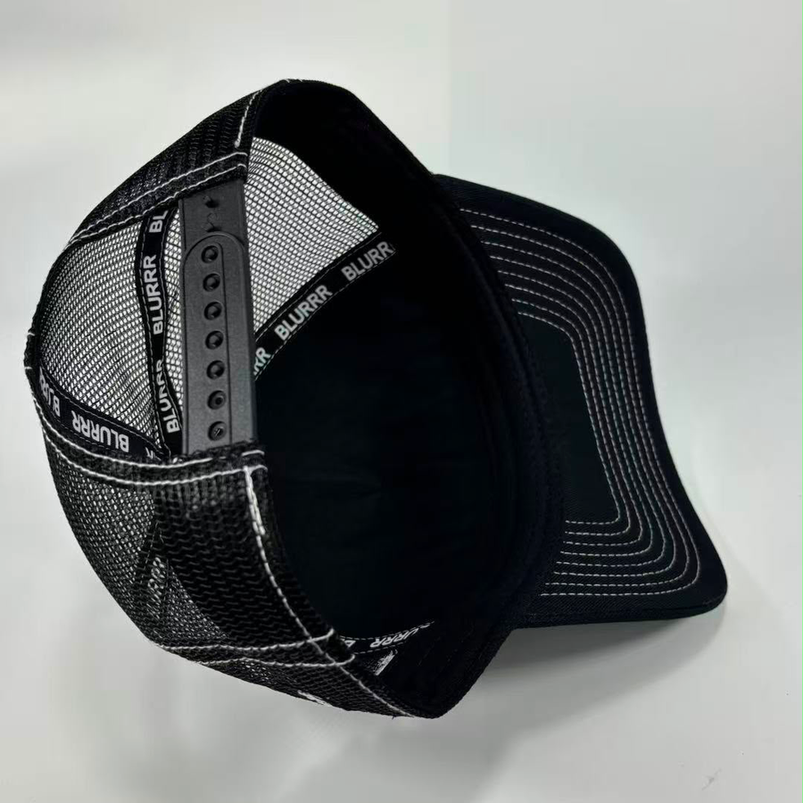 Black mesh trucker cap with white contrast stitching and adjustable snap closure, shown on a light gray background.