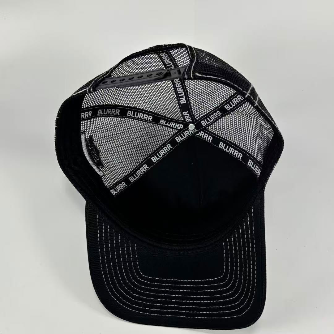 Black trucker-style baseball cap with a black mesh back and white contrast stitching on the visor, photographed on a light gray background.