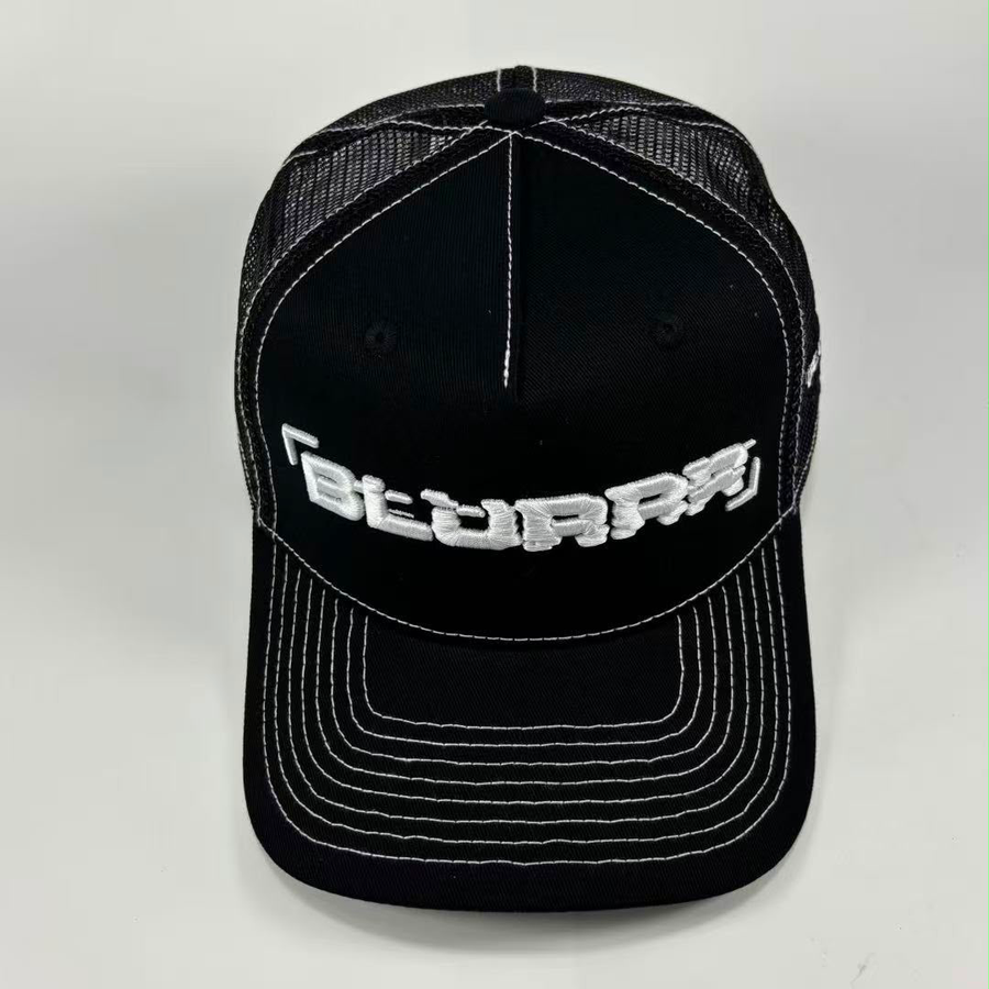 A black trucker-style cap with white contrast stitching and a white embroidered logo reading 'BLURRR' on the front, photographed against a light gray background.