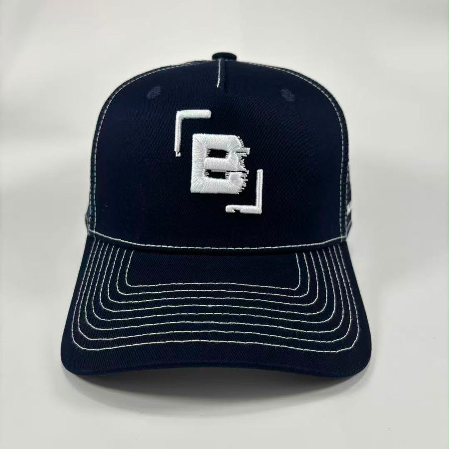 A dark navy blue baseball cap with white contrast stitching and a white embroidered logo on the front, photographed against a light grey background.