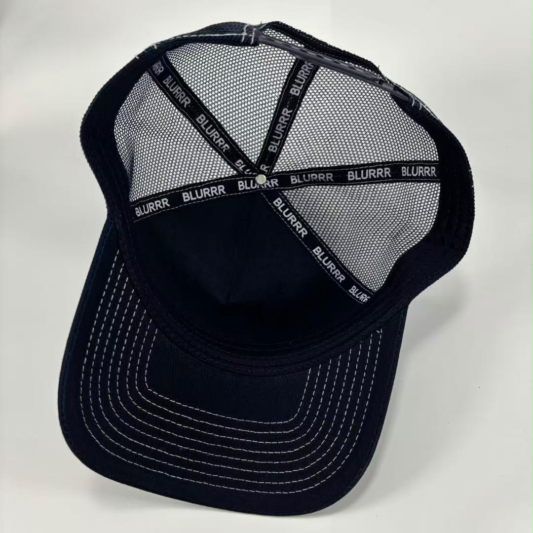A dark navy blue trucker-style baseball cap with a mesh back, white contrast stitching on the brim, and 'BLURRR' printed repeatedly on the back support straps.