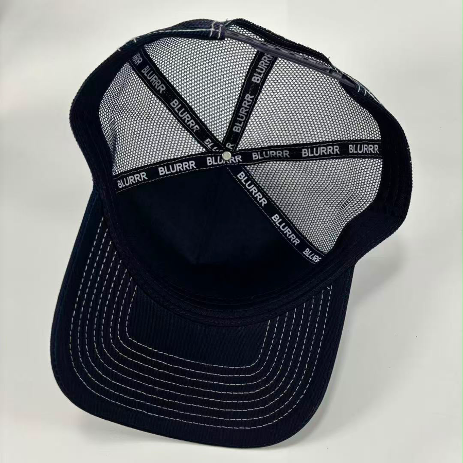 A dark navy blue trucker-style baseball cap with a mesh back, white contrast stitching on the brim, and 'BLURRR' printed repeatedly on the back support straps.