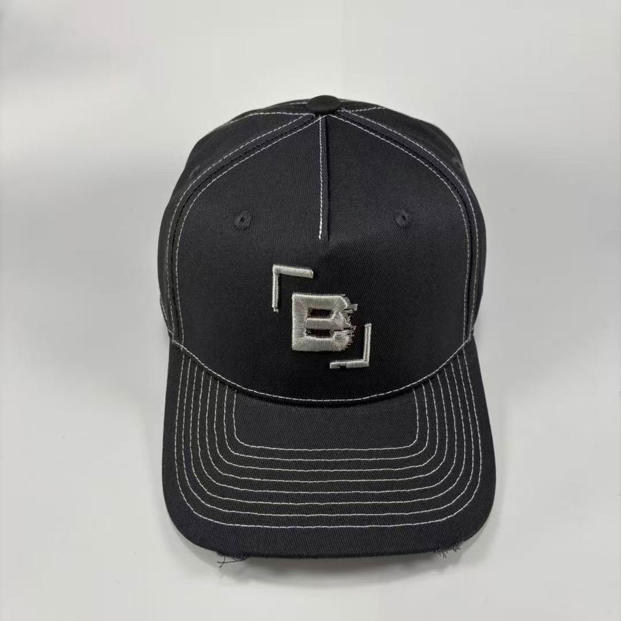 A dark grey baseball cap with white contrast stitching and a silver metallic 'B' logo on the front, photographed against a light grey background.