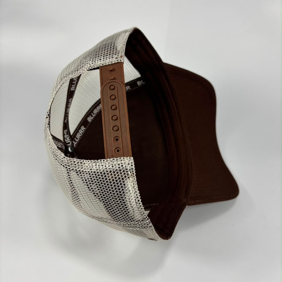 A trucker-style cap shown from an angled top view, featuring a brown visor, brown interior, and a white mesh back with a brown adjustable strap.