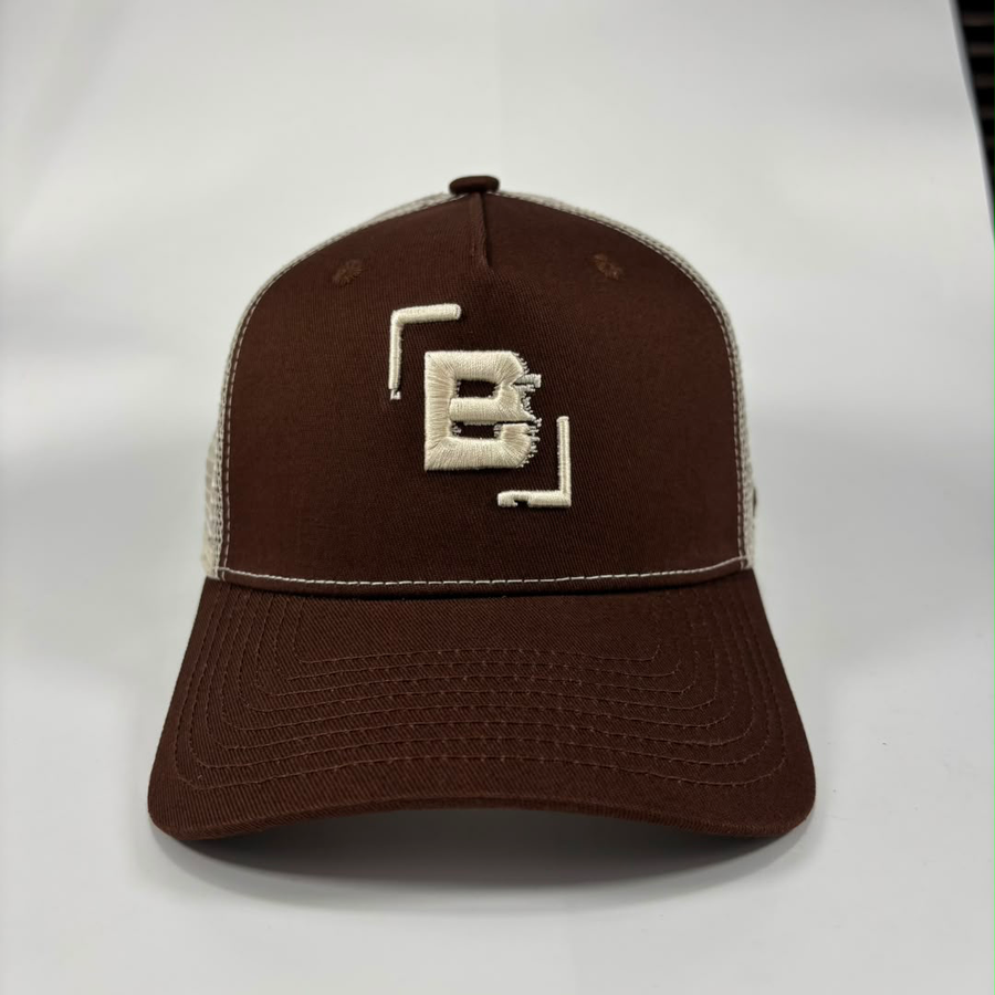 A brown and beige trucker-style baseball cap with a prominent embroidered 'B' logo on the front, set against a plain light gray background.