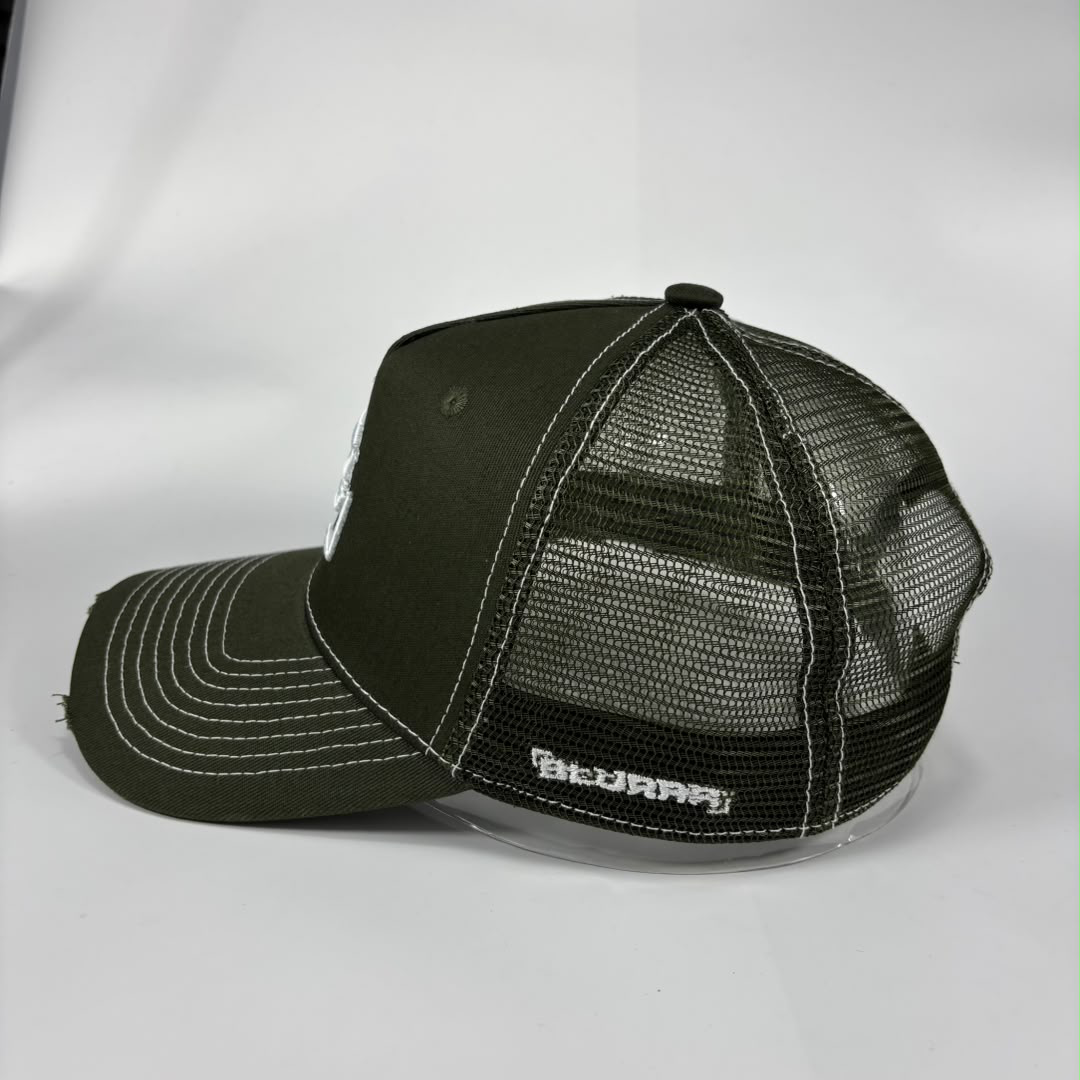 An olive green trucker hat with a mesh back, white contrast stitching, and a white embroidered logo on the side, photographed on a light grey background.