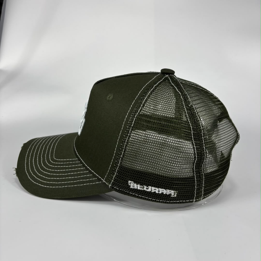 An olive green trucker hat with a mesh back, white contrast stitching, and a white embroidered logo on the side, photographed on a light grey background.